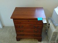 Front view of solid wood nightstand with four drawers and metal handles.