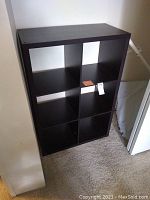 Single dark wood cube organizer shelf with six compartments, photographed indoors against a light wall and carpet.