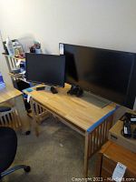 Two Dell computer monitors placed on a wooden desk, one large (approx. 32 inches) and one smaller, photographed to show the items in the lot.
