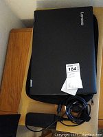 Closed Lenovo Flex 5 laptop on black sleeve with coiled power adapter on wooden table.