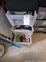 Plastic drawers containing assorted office supplies including glue, markers, tape, and stapler.