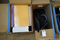 Photo showing filing dividers and some printer paper in a box, alongside black office equipment