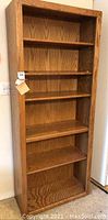 Front view of one oak bookcase showing five shelves with wood grain finish and rectangular shape.