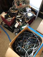 Box containing a mass of assorted black cables and cords including some with visible connectors
