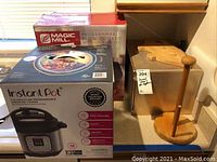 Photo showing Instant Pot Duo Mini 3 quart and Magic Mill slow cooker boxes along with wooden bread box and cutting boards.
