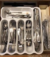 Drawer with white plastic flatware tray holding assorted stainless steel Oneida flatware including knives, forks, spoons, and butter spreaders.