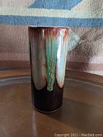Front view of the cylindrical vase showing glaze colors and drip pattern.