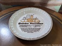 Top down view of the pie plate showing the Quiche Lorraine recipe and illustration in center with decorative border.