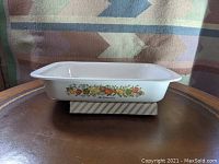 Side view of the CorningWare roasting pan showing the colorful 'Spice of Life' vegetable and fruit pattern on the exterior side.