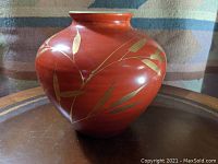 Front side view of large orange-red porcelain vase showing detailed gilt bamboo leaves design.