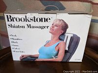 Original box of Brookstone Shiatsu Massager showing usage areas including neck, shoulders, back, arms, calves, and foot soles.