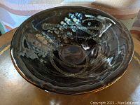 Front angle of dark glazed pottery bowl with freehand drip decoration inside