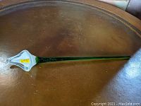 Full view of the long stemmed glass flower resembling a calla lily with green stem and clear petal.