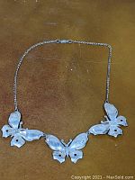 Full view of the vintage Lang sterling silver butterfly necklace, showing the butterfly design and clasp, laid on a brown surface.