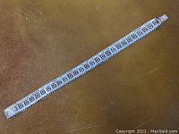 Full view of the 8-inch sterling silver Greek key bracelet on a brown background.