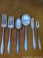 All six pieces laid out on brown surface showing full length of each piece including detailed handles and touch wear.