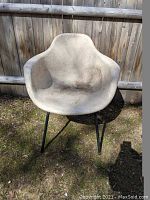 Front view of pink shell chair showing worn and faded surface with armrests and black metal legs.
