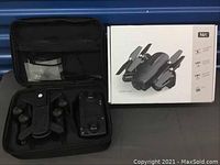 Folded drone, remote controller, and original drone box inside carrying case.