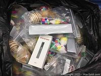 Bag containing individually packaged cat toys with colorful pom-poms, feathers, twine balls, and boxed LED light pointers