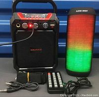 Socovez and Clever Bright Bluetooth speakers side by side with accessories including remote, cables, and strap visible