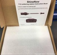 Instruction manual for ShineNow T12 soldering station showing tip installation and function details inside box with protective foam.