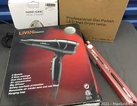 Photo showing Living Basics hair dryer box, nail dryer lamp box, nano ionic facial steamer box, and a red metallic hair straightener.