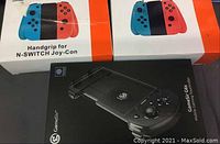 Two Nintendo Switch Joy-Con handgrip boxes on the table alongside a black box for a GameSir G6s mobile gaming controller.