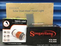 Boxes of the solar dual-head flood light, mosquito travel lamp, and Sougayilang fishing reel with model numbers DL3000 and DL4000.