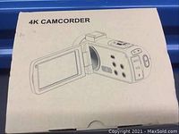 Photo of the original retail box for the 4K camcorder showing a sketch of the camcorder with flip-out screen and control buttons.