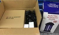 Box opened showing packed items: cardboard box with bulbs, black wiring sockets, and electric mosquito killer box.