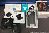 Full view of all items showing 7 earbud packages, a boxed fitness watch, wireless red/black headphones, and a phone case.