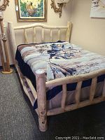 Full view of the rustic log bed with bedding displaying wildlife design and front headboard.