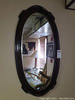 Front view of the oval wooden framed mirror showing overall shape and frame details.