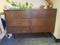 Full front view of dresser showing six drawers, wood finish, tapered legs