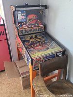 Front-left side view showing full arcade machine with colorful gumballs and front gaming surface