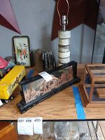 Diagonal view of Oriental diorama in glass case, table lamp, and other items on wooden surface