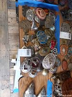 Overall assortment of approximately 40 western belt buckles mostly made of metal with varied designs including horses, horseshoes, floral motifs, and enamel details.