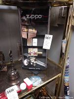 Overall view of Zippo acrylic display case on glass shelf with assorted lighters inside