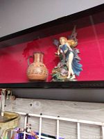 Ceramic pitcher and fairy figurine together on shelf