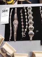 Full set of five sterling silver bracelets laid out on black background for display.