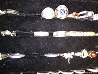 Photo showing seven sterling rings in the middle row under a large "N" signet ring, displaying various stone colors and designs.