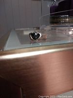 Black heart-shaped stone sterling silver ring on glass surface