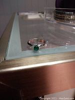 Sterling silver ring with a small round green gemstone set on a simple band