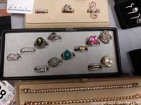 Overview photo showing all 12 sterling silver rings displayed in a black jewelry box insert and a display holder with three small rings.