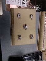 Top view of five silver rings with clear stones displayed on beige ring tray