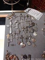 Top view of all pendants arranged on flat surface, showing diverse cross styles, medallions and fish pendant