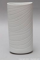 Front view of white porcelain vase showing cylindrical shape and raised swirling pattern