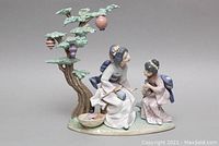Front view of figurine showing adult and child under stylized tree with hanging lanterns