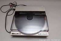 Front three-quarter view of turntable with closed dust cover and attached cables.