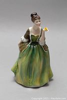 Front view of Royal Doulton 'Fleur' porcelain figurine showing woman in green and brown dress holding a yellow flower.